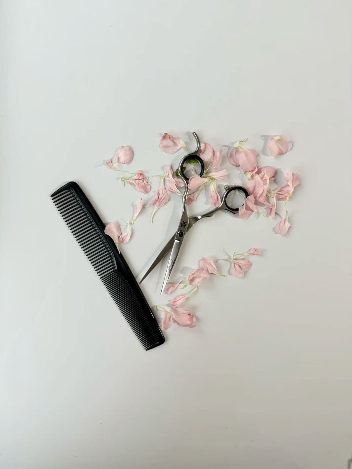 Comb and scissors laid out with flower petals
