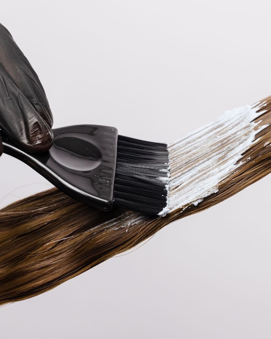 Colour being brushed onto a length of hair